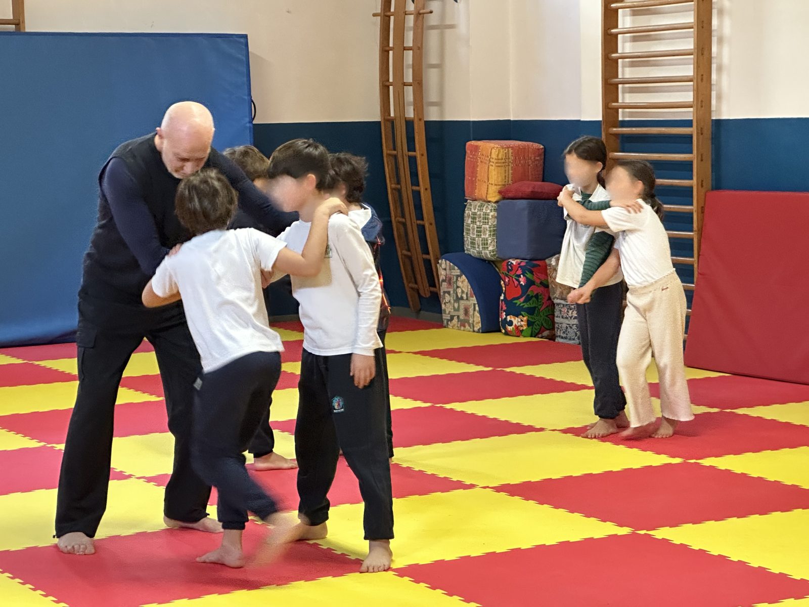 Bambini durante una lezione di judo sul tatami con il maestro