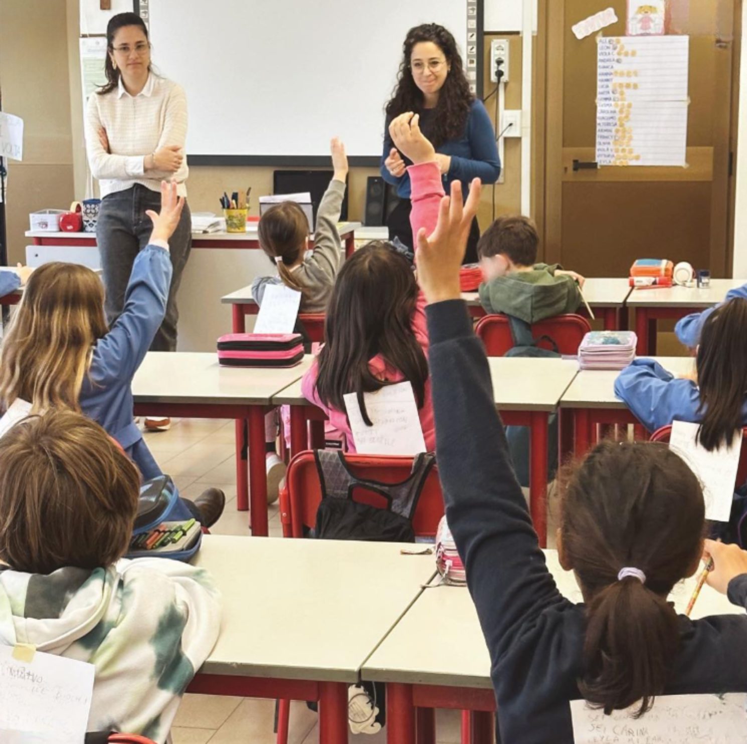 Bambini che alzano la mano durante una lezione di inglese in classe